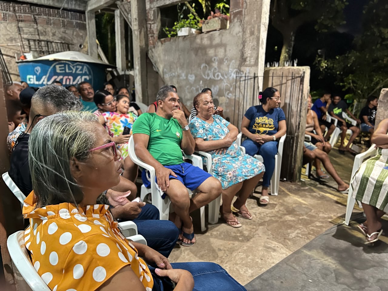 Moradores sentados em roda durante encontro noturno no bairro