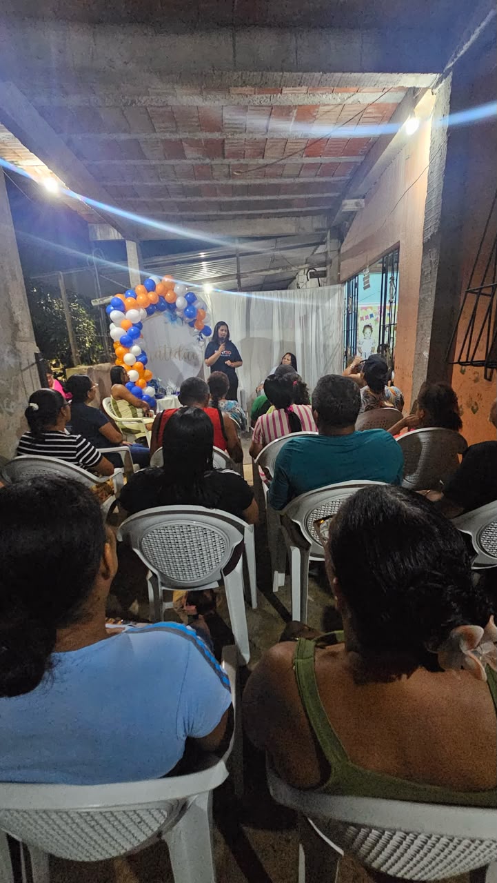 Pessoas reunidas em quintal decorado com arco de balões azuis e laranja