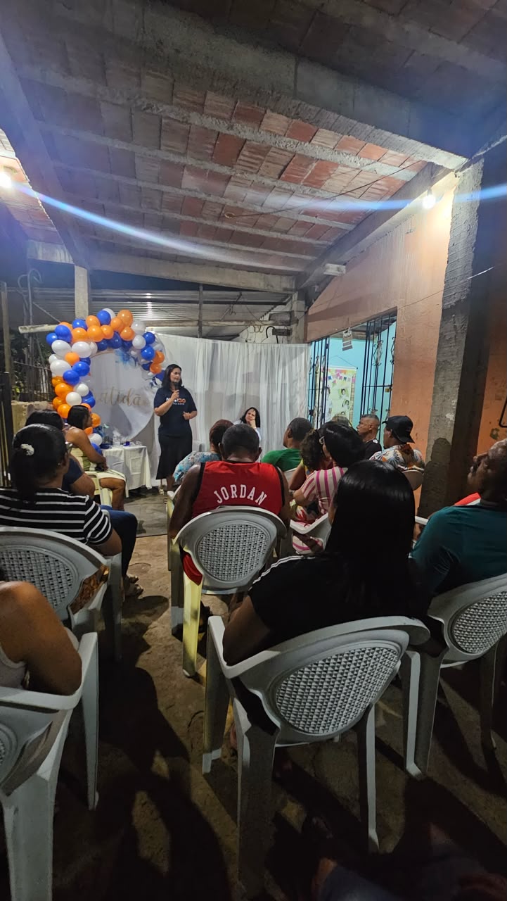 Público sentado acompanhando encontro comunitário de campanha