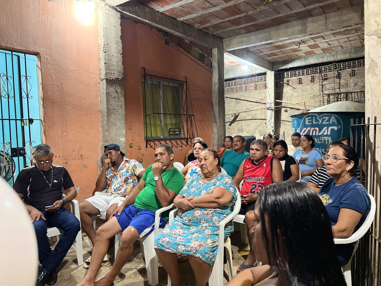 Moradores sentados em frente às casas durante encontro de campanha